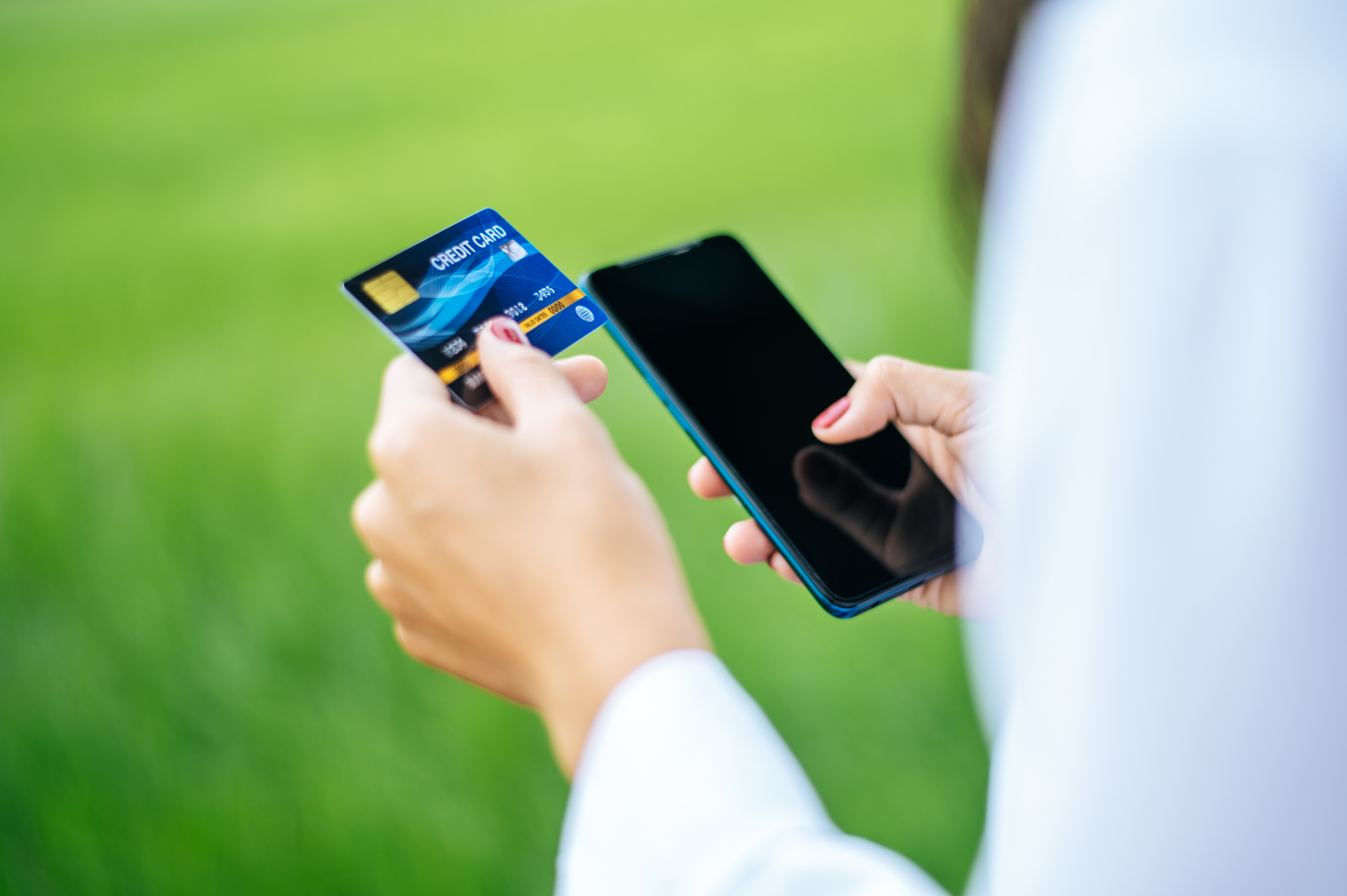  A hand holding a prepaid card beside a phone screen